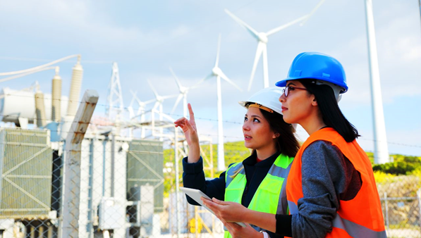 Two women standing in front of wind turbines.